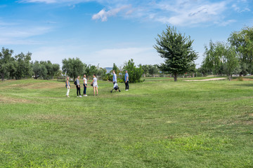 A group of young people on a golf course with a cart to transport the equipment