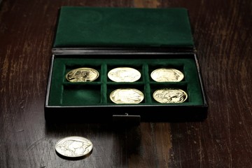 1 ounce American Buffalo gold bullion coins in a coin box on wooden background