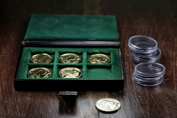 1 ounce American Buffalo gold bullion coins in a coin box on wooden background