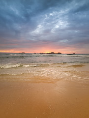Amazing sunset image of sun going down behind cliffs in the ocean