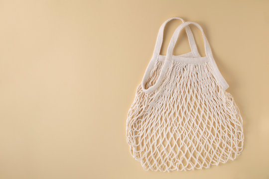Mesh shopping bag at beige background. Zero waste concept.