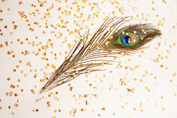 Peacock feather with confetti laid out on a table