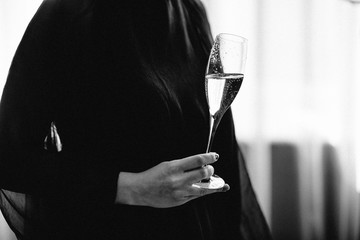 happy woman in black dress looking away and smiling with champagne isolated