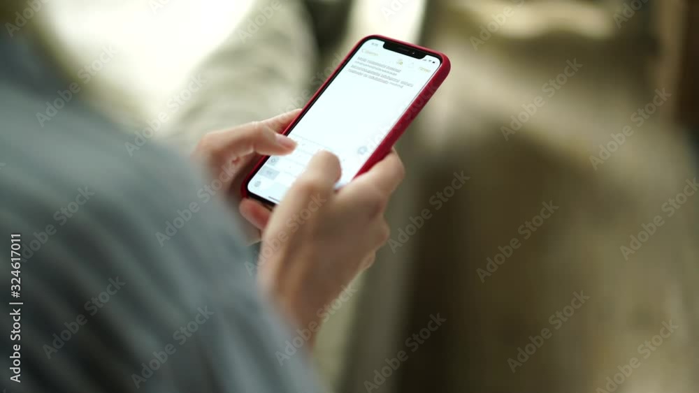 Aufkleber cropped back view of hipster girl holding mobile phone in hands connected to wifi at home typing tex
