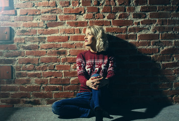 young woman in red pullover near the brick wall