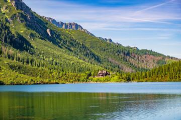 Morskie Oko mountain lake, surrounding forest, Miedziane and Opalony Wierch peaks with Schronisko przy Morskim Oku shelter house in background in Tatra Mountains in Poland