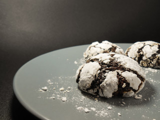 Homemade chocolate cookies. Chocolate brownie cookies in powdered sugar in black background. Selective focus.
