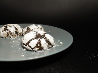 Homemade chocolate cookies. Chocolate brownie cookies in powdered sugar in black background. Selective focus.