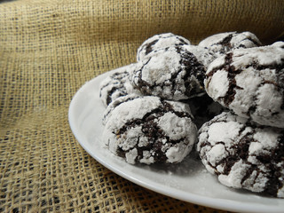 Homemade chocolate cookies. Chocolate brownie cookies in powdered sugar in burlap background. Selective focus.