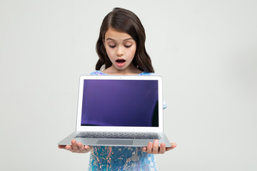 Naklejka premium surprised teenager girl holding a laptop with a mockup for inserting a website on a white studio background