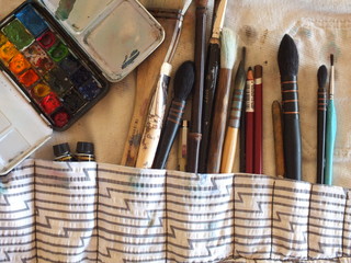  background image of an artist's pencil case with brushes, palette, paints, watercolors, pencils