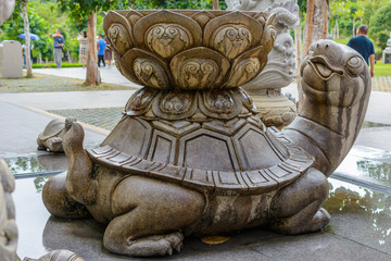 Fototapeta na wymiar Patterned stone turtle with tub and the water on the back on the territory of Buddhist center Nanshan.