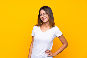 Obraz premium Young woman over isolated yellow background with glasses and happy