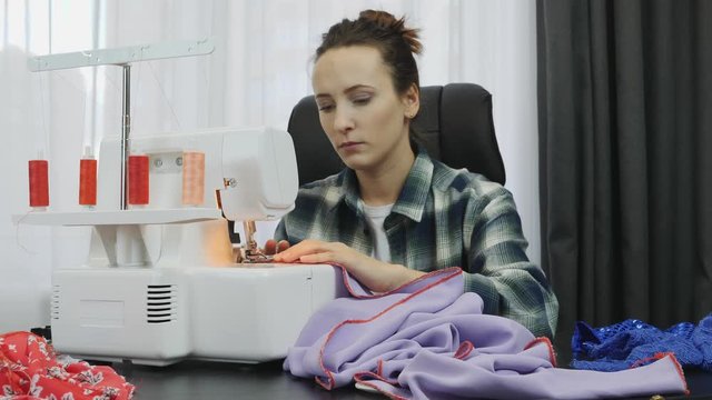 Woman sewing on sewing machine in tailor's studio.  Seamstress works working on dress. Workshop in sewing fabric. Creation and tailoring clothes. Fashion concept