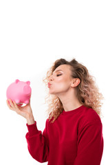 Pretty young girl holds a pink pig moneybox and rejoices