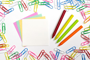 Colorful paper clips, note papers and wax pencils in the centre of composition isolated on white.