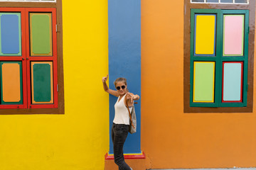 Obraz na płótnie Canvas Blonde girl with sunglasses dancing in front of a colorful facade