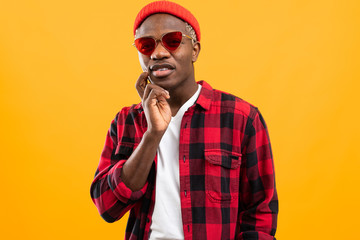 stylish serious black african guy in red retro glasses on orange background with copy space