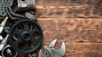 Old car spare parts and wrench on wooden workbench background with copy space.