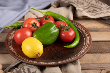 Green pepper with tomatoes and a lemon in a brown platter