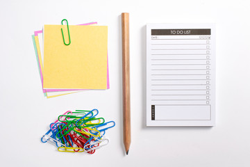 Blank to do list planner with checklist, wooden pencil, colorful paper clips and note papers isolated on white background.