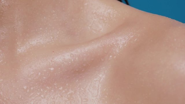 close-up of female collarbone getting water splashes and water drops faling down
