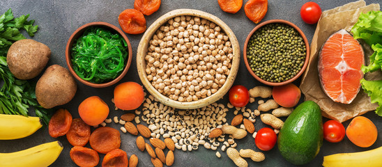 A set of foods high in potassium on a dark background, border. Healthy balanced meal. Top view, flat lay.