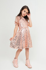 cute teenage girl in full growth in a shiny party dress posing on a white studio background