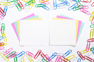 Fototapeta na wymiar Colorful paper clips and note papers in the centre of composition isolated on white.