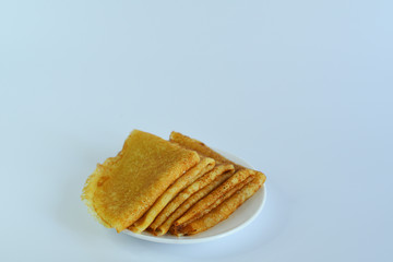 a stack of pancakes with a piece of butter on a fork.Pancake week: thin pancakes with butter and tea on white table.french crepes .Delicious breakfast.