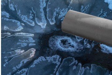 liquid flows from the pipe into the lake and melts the ice. There is a tint. Close-up