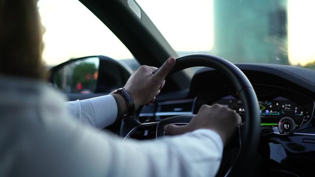 Cropped back view of experienced and confident businessman driver in white shirt holding hands on wheel steering modern vehicle automobile follow rules for safety. Rental car, own driver service