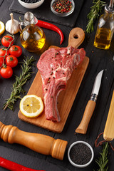 Raw beef antricot on a wooden board. Composition with rosemary, hot pepper and other spices for cooking meat. A look from above.