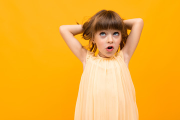 Beautiful little girl in dress isolated on yellow or orange background