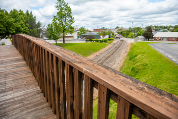 Fototapeta na wymiar Footbridge crossing over railway, wood bridge for pedestrians, blur railroad and landscape