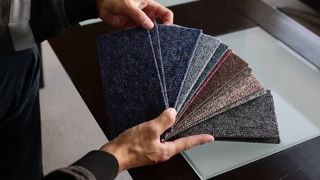 Man chossing floor from the sampler for his new apartment, household furnishing