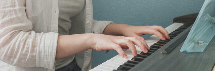 Obraz premium Teenage girl generation in headphones plays the piano, synthesizer, composes music, teenagers' hobby. Education, business, work at home. Creativity, lifestyle