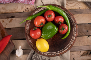 Red tomatoes in a brown platter with green chili and lemon