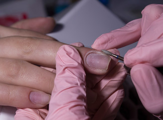 The manicurist processes the client's cuticle with a hardware machine. Hardware manicure.Cuticle removal using a machine with a cutter. Professional manicure in the salon close-up. - obrazy, fototapety, plakaty