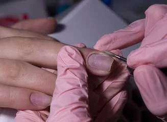 Foto auf Alu-Dibond The manicurist processes the client's cuticle with a hardware machine. Hardware manicure.Cuticle removal using a machine with a cutter. Professional manicure in the salon close-up. © OleJohny
