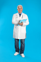 Senior doctor with clipboard on light blue background