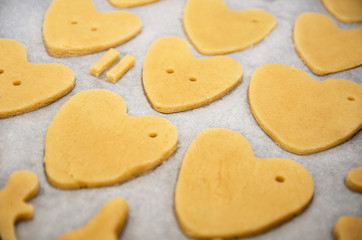 Fototapeta na wymiar Cookies made from dough in the shape of heart lies on the baking sheet before baking