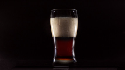 Glass of dark beer on black background