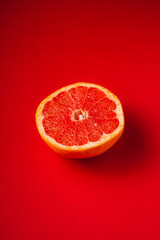 Grapefruit half of fruit, tropical creative minimal food concept, on vibrant red background, lush lava, angle view selective focus