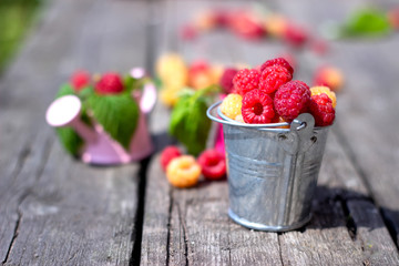 Ripe sweet raspberries on the wooden table in summer time.