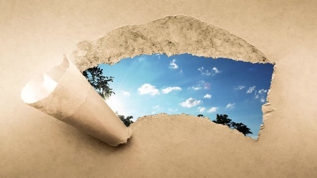 Creative 4k time laps video of fast moving clouds in the blue sky at sunset witn sunflare that are visible through a hole with torn edges in old retro grunge vintage paper.
