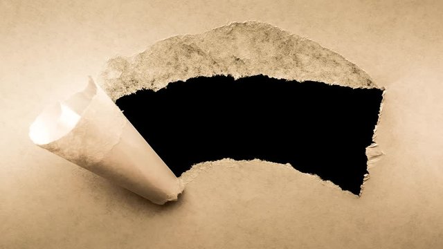 Creative 4k time laps video of a glowing full moon in the night sky with floating clouds, which is visible through a hole with torn edges in old retro grunge vintage paper.