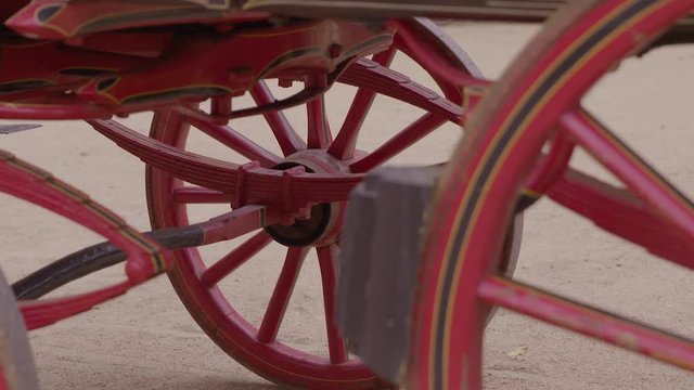 Extreme close up of the underside of a red, painted wagon that is hitched to a couple of horses, at Hamptonne Country Life Museum