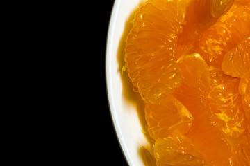 Peeled orange placed in a plate against dark background. Use for fruit concept.