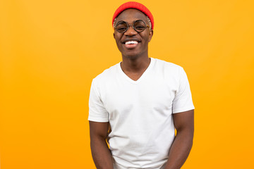 portrait of a stylish smiling sexy african black man in a white t-shirt with glasses on a yellow background